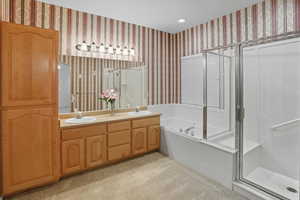 Bathroom featuring light colored carpet, a shower stall, a garden tub, wallpapered walls, and double vanity