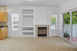 Living room with built in features, light colored carpet, and a fireplace