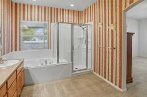 Full bath featuring wallpapered walls, a shower stall, vanity, a garden tub, and light colored carpet