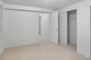 Bedroom with light carpet, a textured ceiling, and a closet