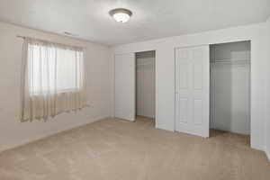 Bedroom featuring two closets, light carpet, and a textured ceiling