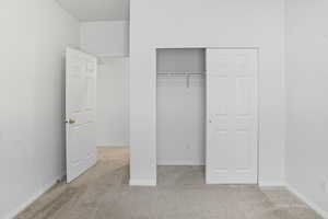 Bedroom with light colored carpet and a closet