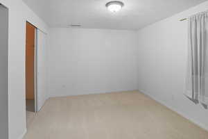 Bedroom featuring light carpet, a closet, and a textured ceiling