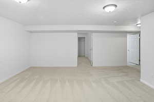 Finished basement with a textured ceiling and light carpet