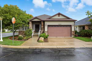 View of front of house with stone siding, driveway, and an attached garage