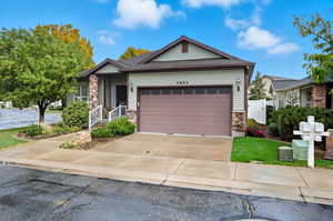 View of front of home featuring stone siding, a garage, and driveway