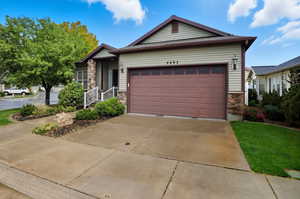 Ranch-style home featuring stone siding, driveway, and an attached garage