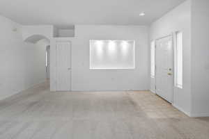 Foyer with light colored carpet, arched walkways, light tile patterned floors, and recessed lighting
