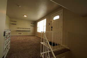 Foyer with dark colored carpet and a textured ceiling