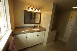 Full bathroom featuring vanity, a tile shower, dark wood-style flooring, and a textured ceiling