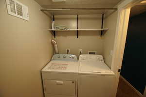 Laundry area with a textured ceiling, carpet, and washing machine and clothes dryer