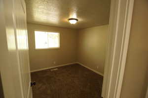 Unfurnished room with dark carpet and a textured ceiling