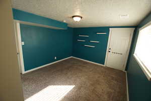 Spare room with dark colored carpet and a textured ceiling