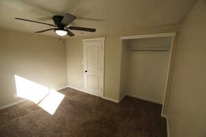 Unfurnished bedroom with a textured ceiling, carpet floors, a closet, and ceiling fan