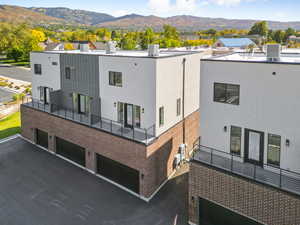 Back of property with brick siding, an attached garage, a mountain view, and a patio