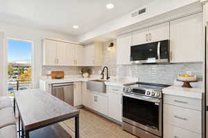 Kitchen featuring stainless steel appliances, decorative backsplash, light stone countertops, and recessed lighting