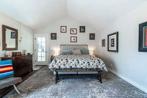 Primary bedroom with lofted ceiling and dark wood-type flooring