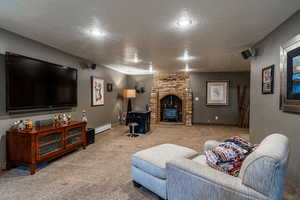 Carpeted living area featuring a textured ceiling, a wood stove, and baseboard heating