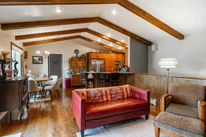 Living area with recessed lighting, a chandelier, dark wood finished floors, baseboard heating, and a wainscoted wall