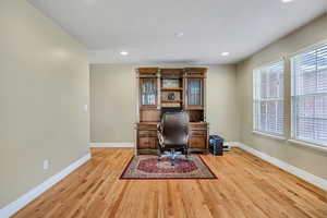 Home office with light wood finished floors and recessed lighting