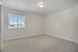 Empty bedroom featuring light carpet and baseboards