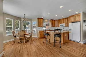 Kitchen with light countertops, white appliances, a kitchen island, and recessed lighting