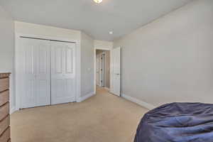 Bedroom featuring light carpet and a closet