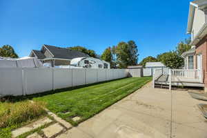 Fenced backyard featuring a wooden deck and a shed