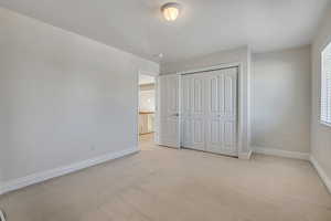 Unfurnished bedroom with light colored carpet and a closet