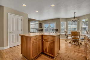 Kitchen with recessed lighting, light countertops, light wood-type flooring, a textured ceiling, and pendant lighting