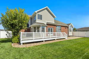 Back of house with a fenced backyard, a deck, brick siding, and stucco siding