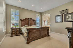 Master bedroom featuring light carpet, recessed lighting, and ensuite bath