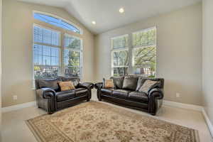 Living area with light colored carpet, lofted ceiling, healthy amount of natural light, and recessed lighting