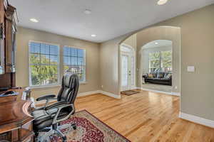 Office space with recessed lighting, arched walkways, and light wood-style flooring