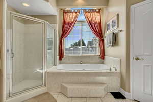 Master full bath featuring a shower stall, a jetted tub, and light tile patterned flooring