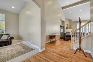 Living area featuring healthy amount of natural light, arched walkways, light wood-style floors, recessed lighting, and high vaulted ceiling
