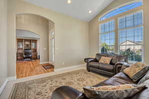 Living room featuring a desk, arched walkways, recessed lighting, and high vaulted ceiling