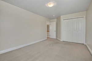 Unfurnished bedroom with light carpet and a closet