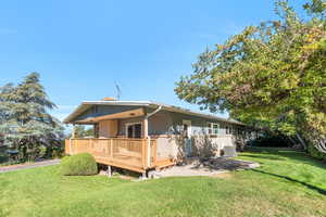 Rear view of property with a yard, a deck, brick siding, and a patio area