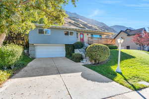 View of front facade featuring concrete driveway, a garage, stairway, a front yard, and a deck with mountain view