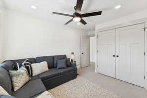 Carpeted living room with recessed lighting and ceiling fan