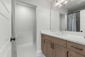 Bathroom with vanity, light tile patterned floors, and a tile shower