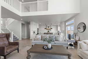 Living area featuring light wood-style flooring, recessed lighting, stairway, and a high ceiling