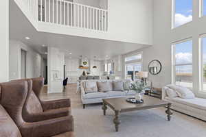 Living area featuring a towering ceiling, healthy amount of natural light, light wood-type flooring, and recessed lighting