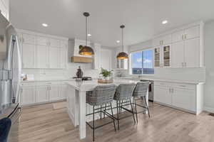 Kitchen featuring hanging light fixtures, a kitchen breakfast bar, stainless steel appliances, decorative backsplash, and recessed lighting