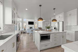 Kitchen with tasteful backsplash, open floor plan, white cabinets, stainless steel appliances, and recessed lighting