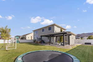Back of house with a trampoline, a pergola, and a patio