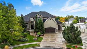 View of front of house featuring stone siding, driveway, a garage, a front yard, and stucco siding