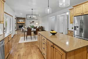 Kitchen with decorative light fixtures, light stone countertops, light wood-style flooring, light brown cabinetry, and recessed lighting