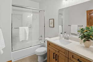 Full bath featuring bath / shower combo with glass door, vanity, and light tile patterned flooring